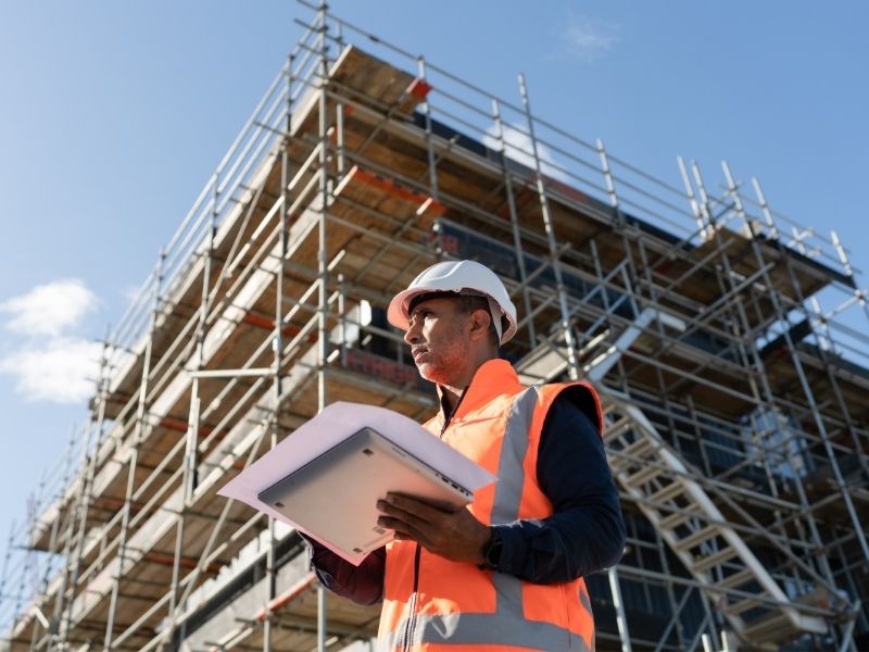 Civil engineer reviewing plans at an active construction site to help guide a successful development project.
