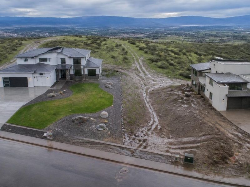 Aerial view of neighboring properties on sloping terrain showing site grading and stormwater drainage designed to direct runoff away from adjacent lots in Denver, CO.

